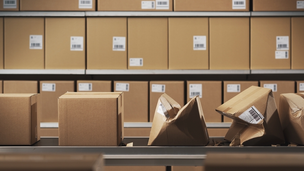 Cardboard boxes, some damaged, moving on a conveyor in a packaging line.