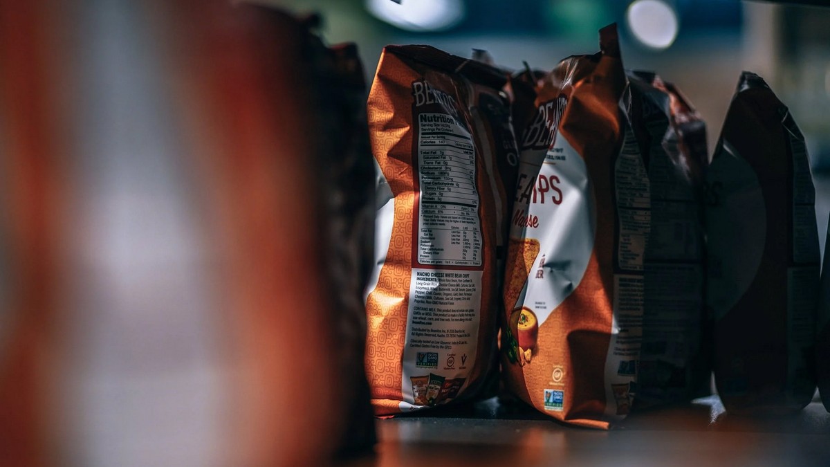 Bags of potato chips on a packaging line, viewed close-up with shallow depth of field.