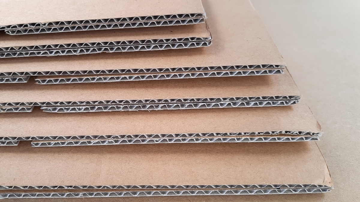 Corrugated board blanks staged for an automated case erector in secondary packaging.